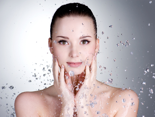 woman splashing face with water following skincare trends